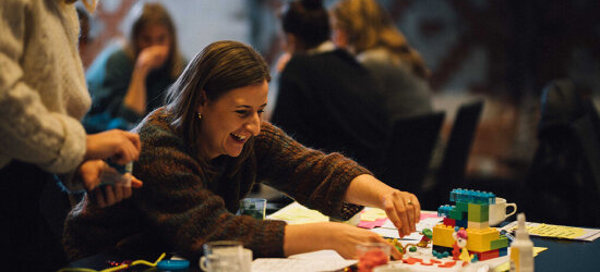 Smilende kvinne ved et workshopbord.