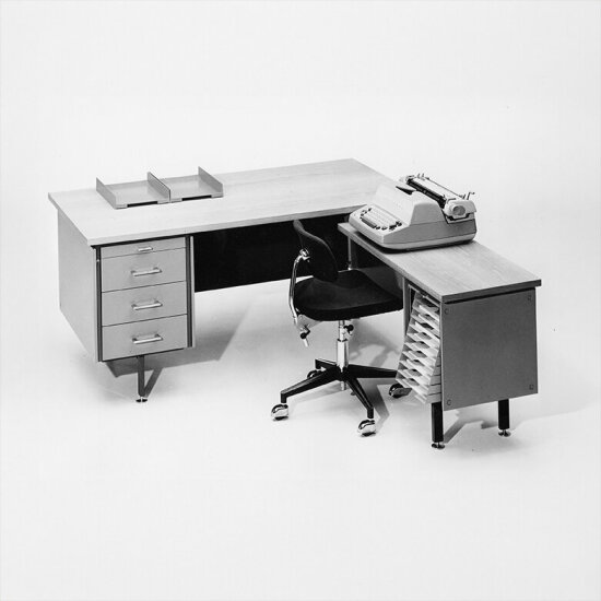 Svart-hvitt-bilde av et retro hjørneskrivebord med en skrivemaskin.
