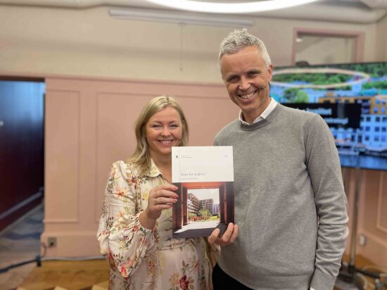 To smilende mennesker viser frem regjeringens nye arkitekturstrategi