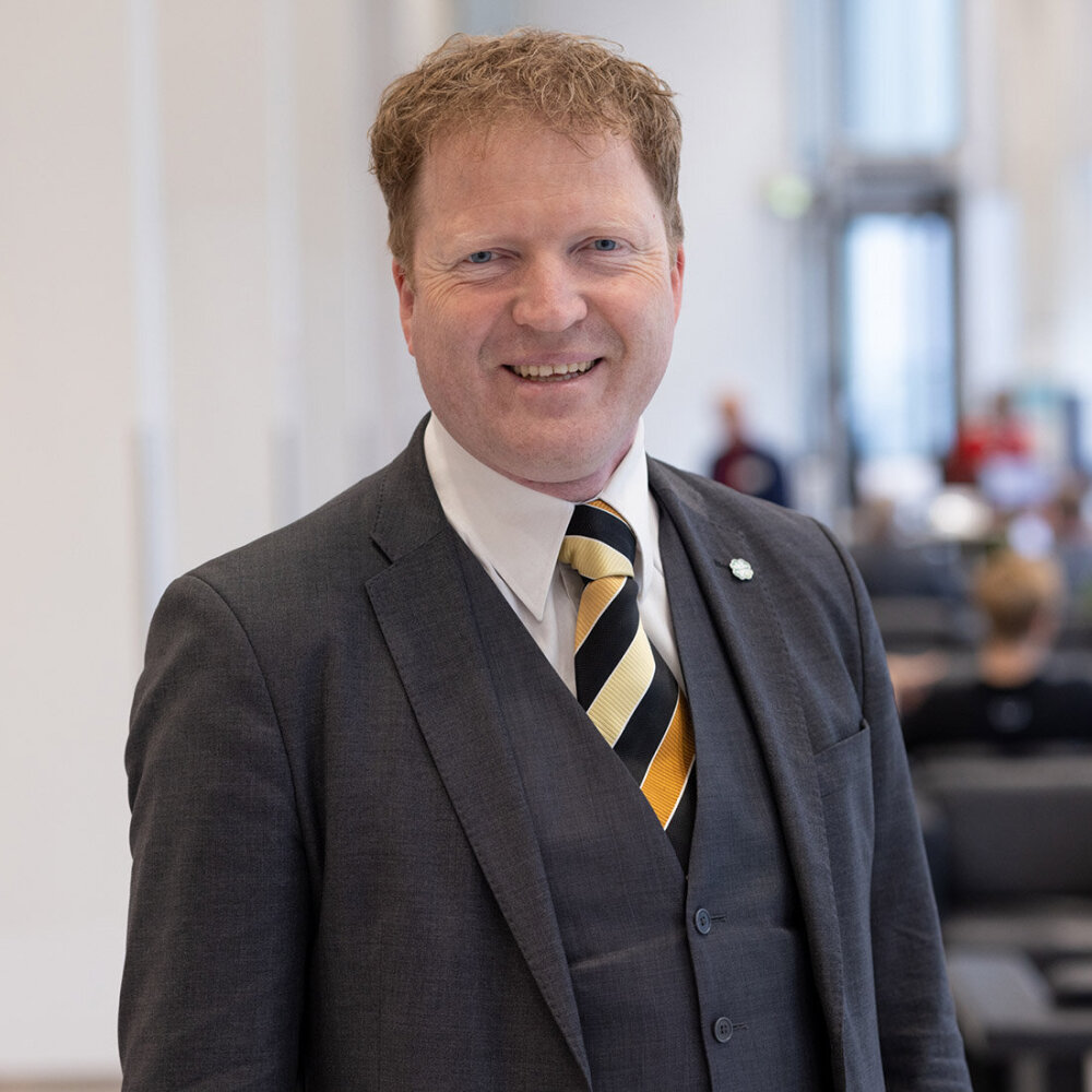 Portrett av en smilende mann i dress. 