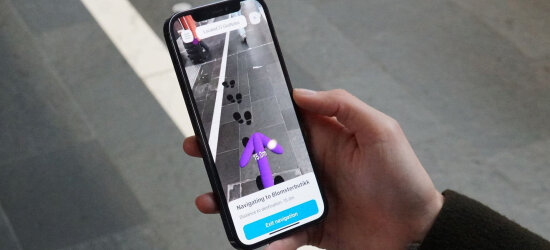 Bildet viser en mobiltelefon med Sopra Sterias app illumie, som tilbyr virtuell synshjelp på mobilen.