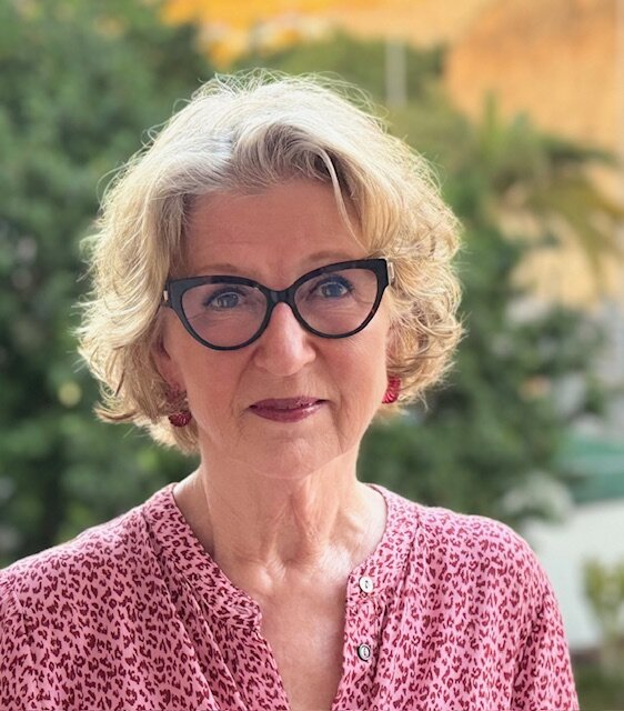 Portrettbilde av en dame med lyst hår og kattøye-briller med sort innfatning, .
