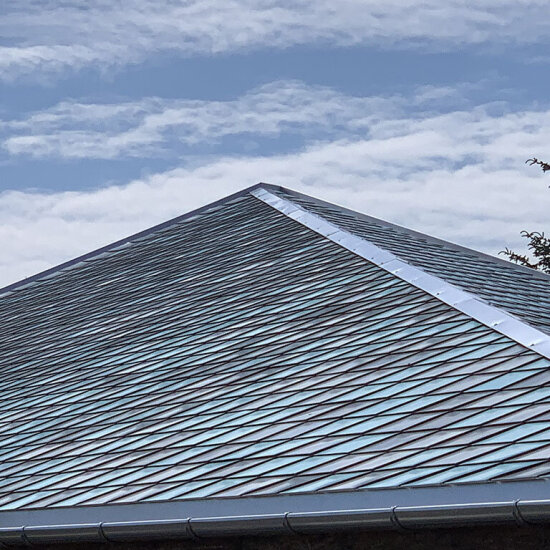 Et tak med kvadratiske plater av avkapp fra blikkenslagerindustrien. I bakgrunnen ser vi blå himmel med hvite skyer.