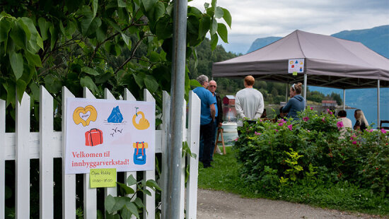 Innbyggerverksted i Aurland kommune: Mennesker står under et partytelt på kaia i Aurland.