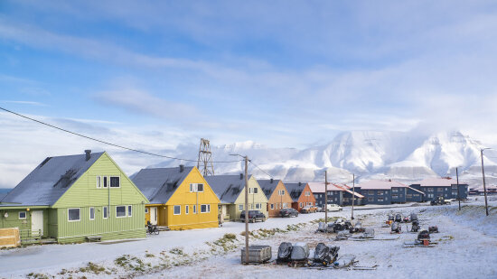 Fargerike hus på Svalbard med hvite fjell i bakgrunnen