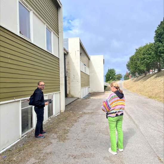 En mann og en kvinne står foran en nedslitt bygning.
