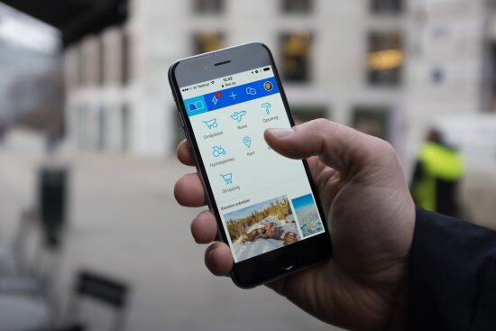 Bildet viser en hånd som holder en mobil med finn.no app i bruk