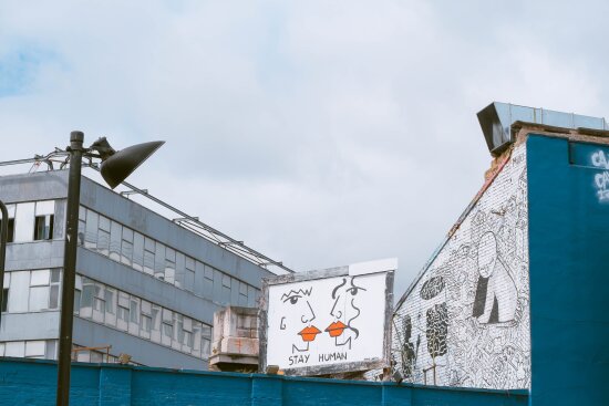 Gatekunst med teksten «Stay Human» i urbant miljø.