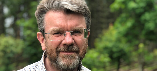 Gunnar Ridderstrøm, Førsteamanuensis, Fakultet for landskap og samfunn, Institutt for by- og regionplanlegging,NMBU. Portrettbilde, i bakgrunnen grønne trær.