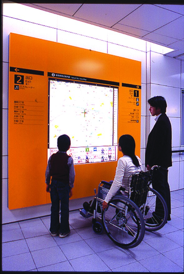 This shows a family watching the information screen at the station