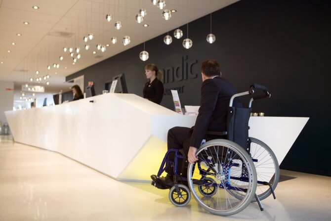 CEO of Scandic Oslo Airport testing the reception accessibility with a wheelchair