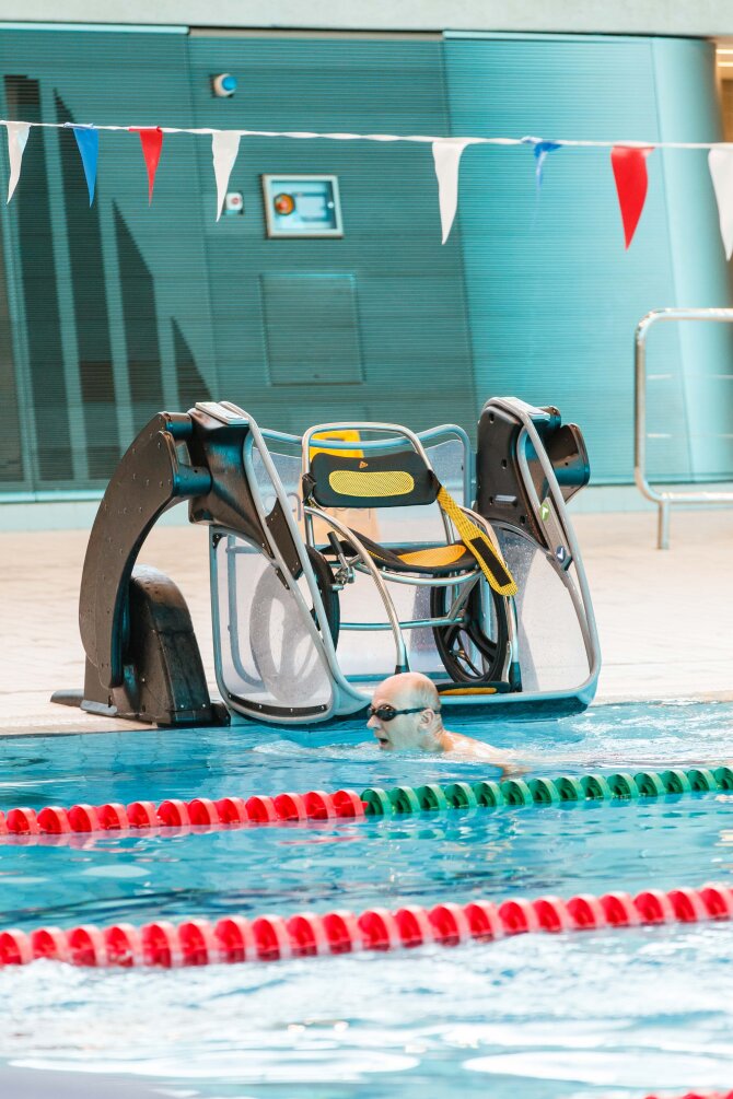 man swimming with his wheelchair left on the pool ramp