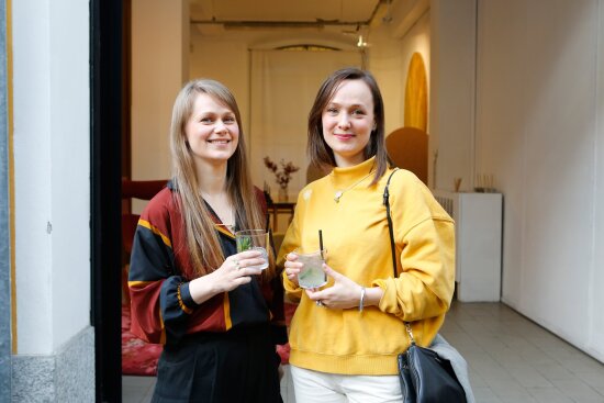 Åshild Kyte og Vera Kleppe står foran utstillingslokalet. Vera Kleppe har en knallgul genser. Begge har et glass i hånden.