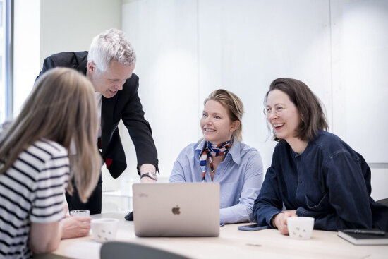 Fire personer ser på en Mac-skjerm og smiler.