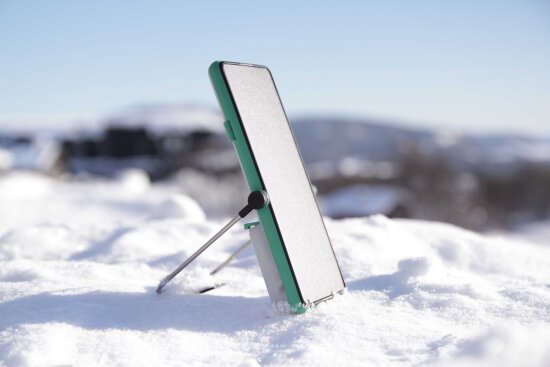 Smarttelefon med stativ i snøen.