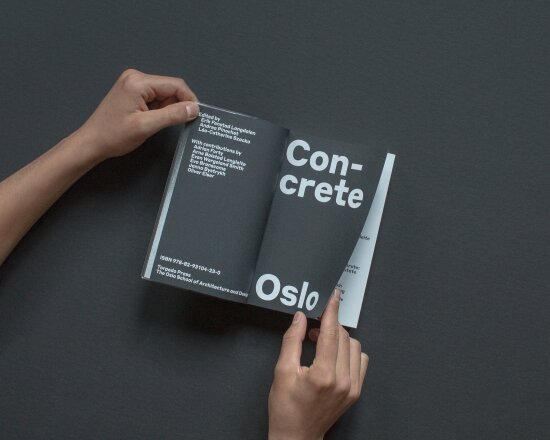 Hender som holder i hvert sitt hjørne av en oppslått bok – boken Concrete Oslo.