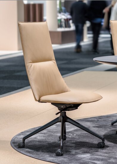 Høyrygget konferansestol i lysebrunt skinn.