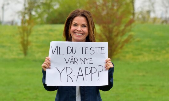 Meteorolog holder opp håndskereven plakat med teksten «Vil du teste vår nye Yr-app?»