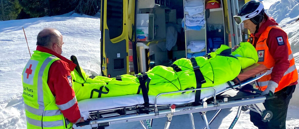 En person ligger på båre iført en knall gul Thermosaver-bag. To personer fra Røde Kors er i ferd med å løfte pasienten på båren inn i en sykebil.