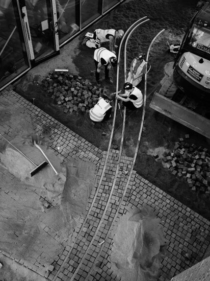 Anleggsarbeidere sitter og monterer lyskildene på bakken. Foto