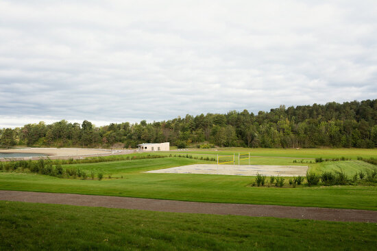 Stor gressslette i strandsonen med volleyballbane. Foto