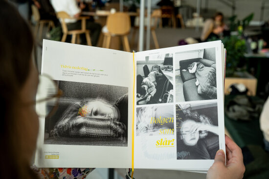 Hender som holder en bok åpen. Sidene viser svart-hvitt bilder med gul skrift over.