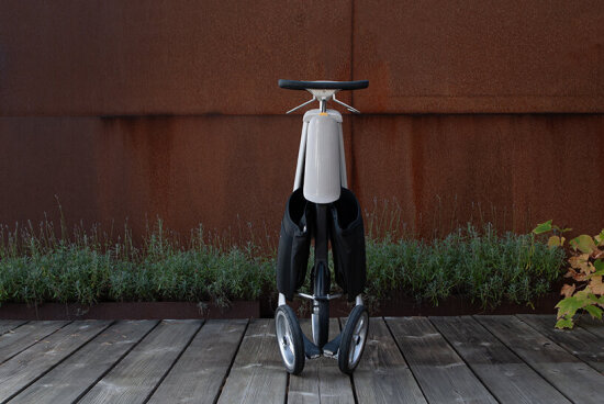 Hvit trehjuling med ratt som er slått sammen og klar til å bæres med seg.