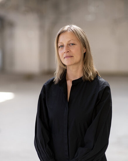 Portrett av Guri Mo, en kvinne med lyst halvlangt hår, kledd i en løstsittende sort skjorte/bluse.
