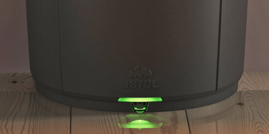 Nærbilde av en vedovn med et grønt lys nederst.