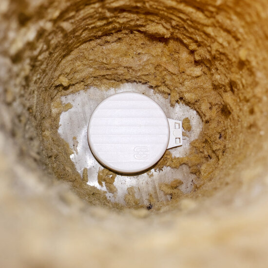 Et hull i et brunt isolasjonsmateriale. I bunnene er det et hvitt lokk.