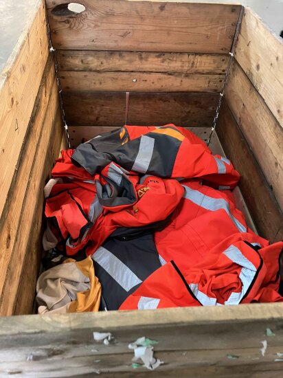 Oransje arbeidsklær ligger slengt oppi en trekasse.