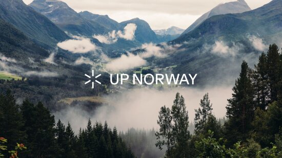 Landskapsbilde av den norske fjellheimen med lave skyer over og skog i forgrunnen.