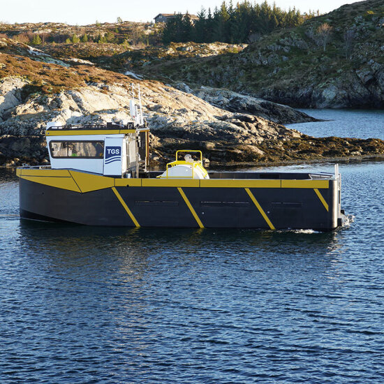En liten fiskebåt med svaberg i bakgrunnen