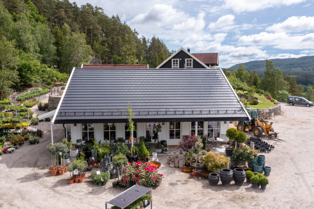 Hvitt hus med skråtak dekket av solcelletakstein. 