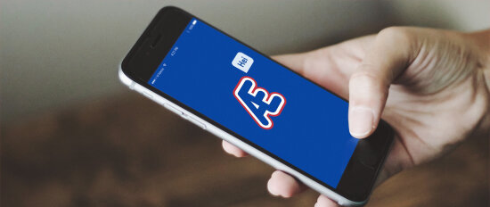 Æ-appens oppstartsbilde på en iPhone som holdes i en hånd.