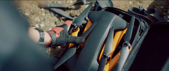 Mann pakker ut drone av sekk.